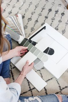 a woman is sitting on the floor with some paint samples