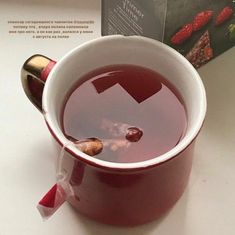 a red cup filled with liquid next to a book