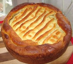 a baked bread dish sitting on top of a wooden cutting board next to a window