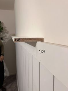 a person standing next to a white wall with a ruler on it's side