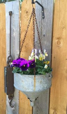 purple and white flowers are in a hanging bucket