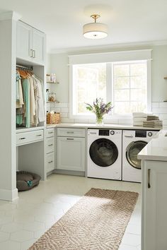 a washer and dryer in a white laundry room with lots of cabinet space