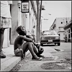 a young boy sitting on the side of a street