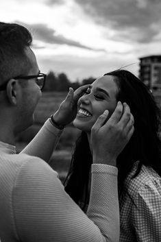 a man and woman standing next to each other with their hands on their faces as they laugh