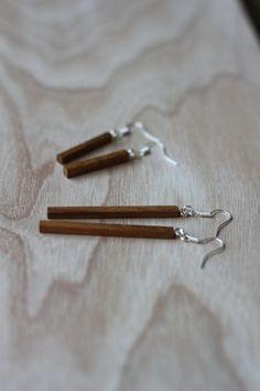 two pairs of wood and silver earrings on a wooden tablecloth with metal hooks hanging from them