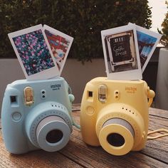 two cameras sitting on top of a wooden table