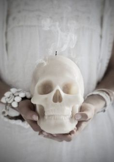 a person holding a fake human skull in their hands with flowers on the arm and wrist