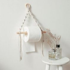 a white shelf with a roll of toilet paper hanging from it's side next to a jar