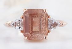 a pink diamond ring with three diamonds around it