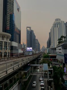 a city street filled with lots of traffic next to tall buildings and skyscrapers in the distance