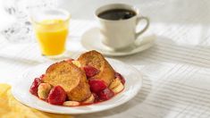 two pieces of french toast on a plate with strawberries and almonds next to a cup of coffee