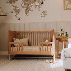 a baby's room with a wooden crib and wall map on the wall