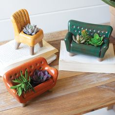 three ceramic planters sitting on top of a wooden table next to an open book