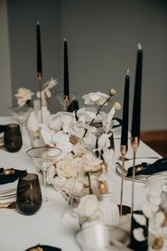 the table is set with black and white dishes, candles, and floral centerpieces