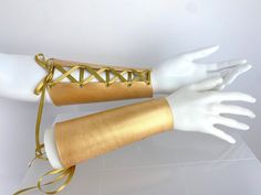 a white mannequin's arm with gold bracelets on top of it