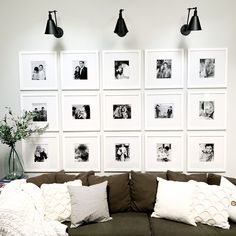 a living room filled with lots of pictures on the wall above a brown couch and white pillows