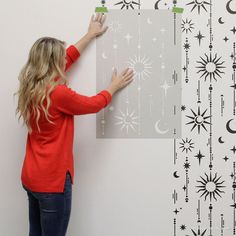 a woman is painting a wall with stars and moon stencils