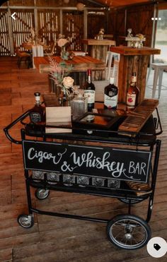 a bar cart sitting on top of a wooden floor next to a table filled with bottles