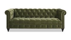 a green velvet couch with studding on the arms and back, in front of a white background