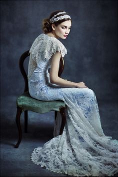 a woman sitting on top of a green chair wearing a white dress and headband