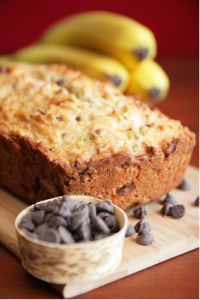 a loaf of bread sitting on top of a wooden cutting board next to two bananas