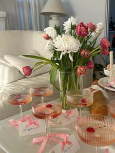 a table topped with wine glasses filled with pink and white flowers