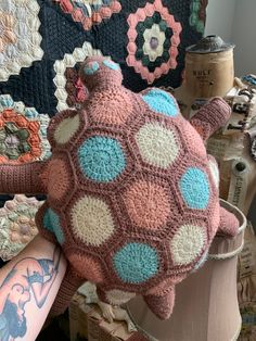 a crocheted turtle pillow sitting on top of a table next to a lamp