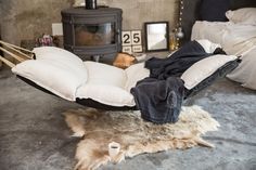 a person laying in a hammock on the floor next to a fire place