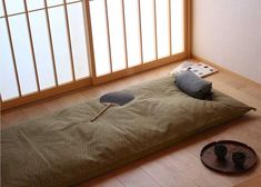 a bed that is on the floor in front of a window with a paddle and two cups