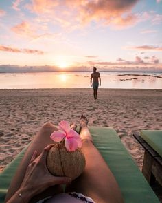 a woman laying on top of a beach under a pink flower