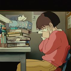 a person sitting at a desk with stacks of books in front of him and holding a phone to their ear