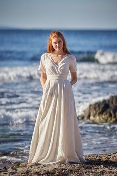 a woman in a white dress standing on the beach