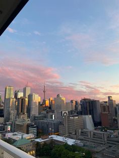 the city skyline is seen at sunset from an apartment balcony in sydney, australia with pink and blue clouds