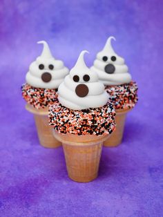 three cupcakes with white frosting and sprinkles in cones on a purple background