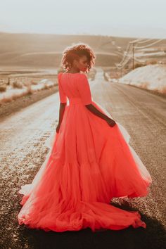 a woman in an orange dress is standing on the road