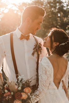 a bride and groom standing close together in the sun with their backs to each other