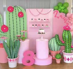 a table topped with lots of pink and green decorations next to potted cacti