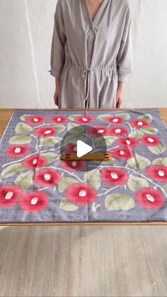 a woman standing in front of a table with a flower design on it