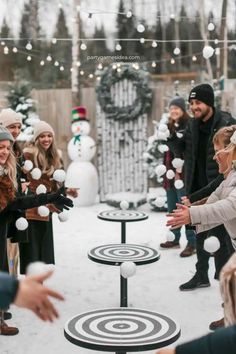 a group of people playing with snowballs in the middle of a snowy yard area