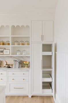 a kitchen with white cabinets and wooden floors