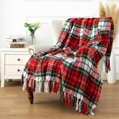 a red and black plaid blanket sitting on top of a chair next to a white table