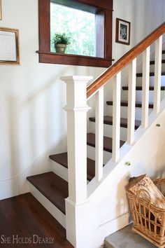 there is a basket sitting on the floor next to the stairs in this house with wood handrails