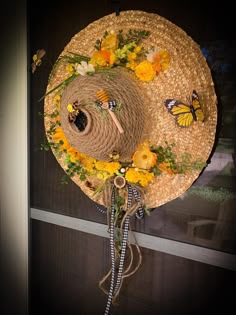 a straw hat with yellow flowers and butterflies on it hanging from a window sill