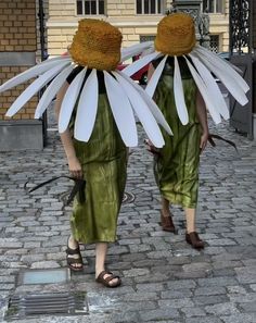 two women walking down the street with large white flowers on their heads