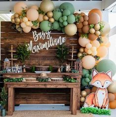 a baby's first birthday party decorated with balloons, greenery and woodland animals