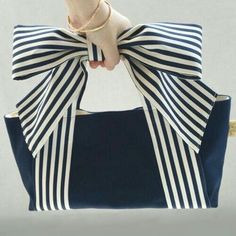 a woman's hand is holding a blue and white purse with a bow on it