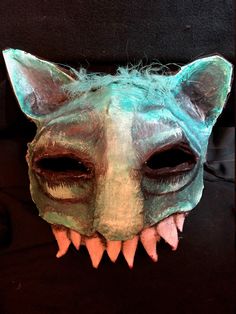 an animal mask with large teeth on it's face and mouth is painted green