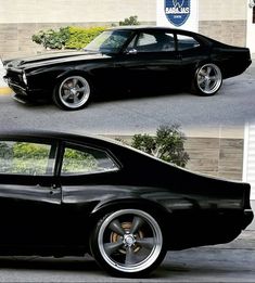 an old black muscle car parked in front of a building with chrome wheels and rims