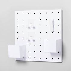 a white wall mounted with four square magnets and two rectangular ones on the opposite side