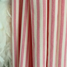 pink and white striped curtains with feathers hanging on the wall behind them in front of a window